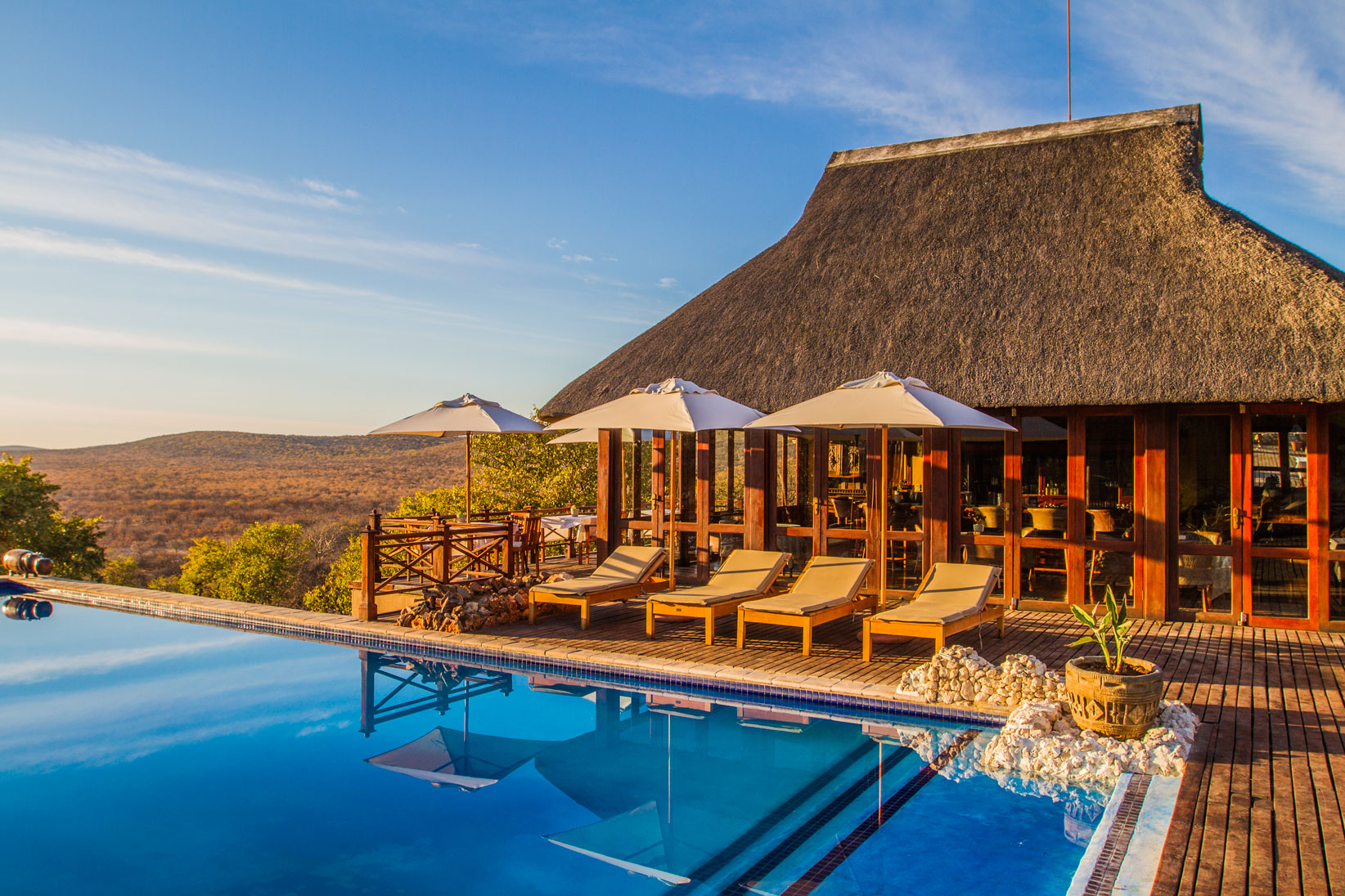 Epacha Game Lodge & Spa, Epacha Private Game Reserve, Epacha Wildtierreservat, Etosha Nationalpark, Infinity Pool, Liegestühle, Poolbar, Sonnenschirme, Afrikarma, Afrikarma Safaris, Afrikarma Safaris – Wildnis. Hautnah., afrikarma.de