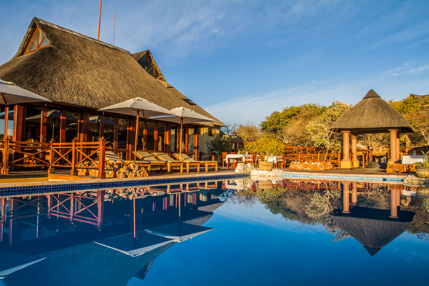 Epacha Game Lodge & Spa, Epacha Private Game Reserve, Epacha Wildtierreservat, Etosha Nationalpark, Infinity Pool, Liegestühle, Poolbar, Sonnenschirme, Afrikarma, Afrikarma Safaris, Afrikarma Safaris – Wildnis. Hautnah., afrikarma.de