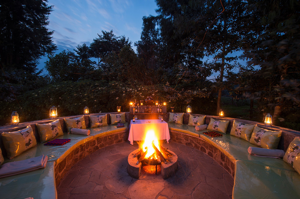 Amakoro Songa Lodge: Feuerstelle Bäume, Feuerstelle, Sitzgelegenheit, Tisch, Amakoro Songa Lodge, Gorilla Tracking, Volcanoes National Park, Afrikarma, Afrikarma Safaris, Afrikarma Safaris. Wildnis. Hautnah., afrikarma.de