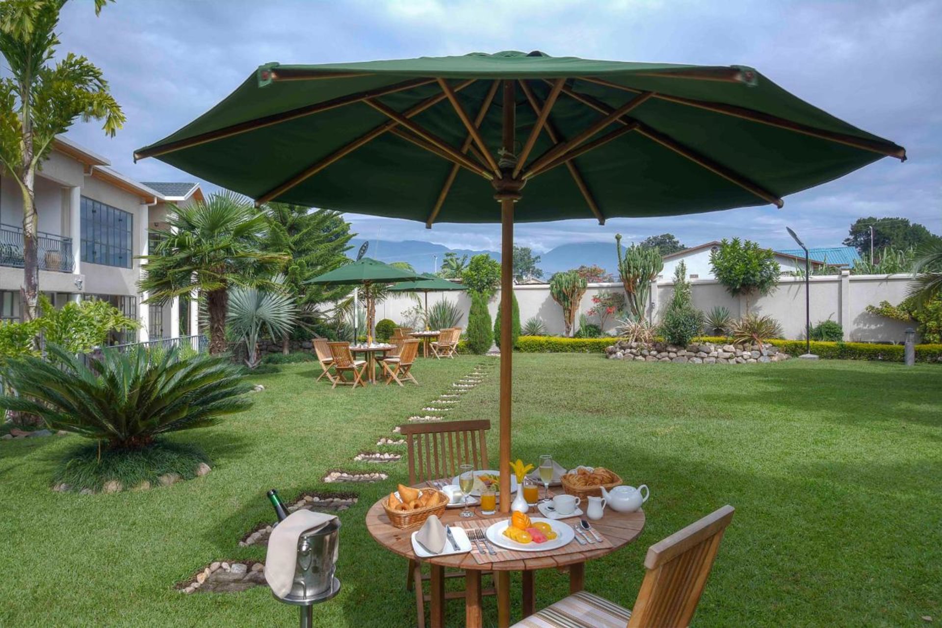 Frühstück, Garten, Pflanzen, Schirm, Stühle, Tisch, The Bishop's House, Gorilla Tracking, Ruhengeri, Volcanoes National Park, Afrikarma, Afrikarma Safaris, Afrikarma Safaris. Wildnis. Hautnah., Afrikarma.de