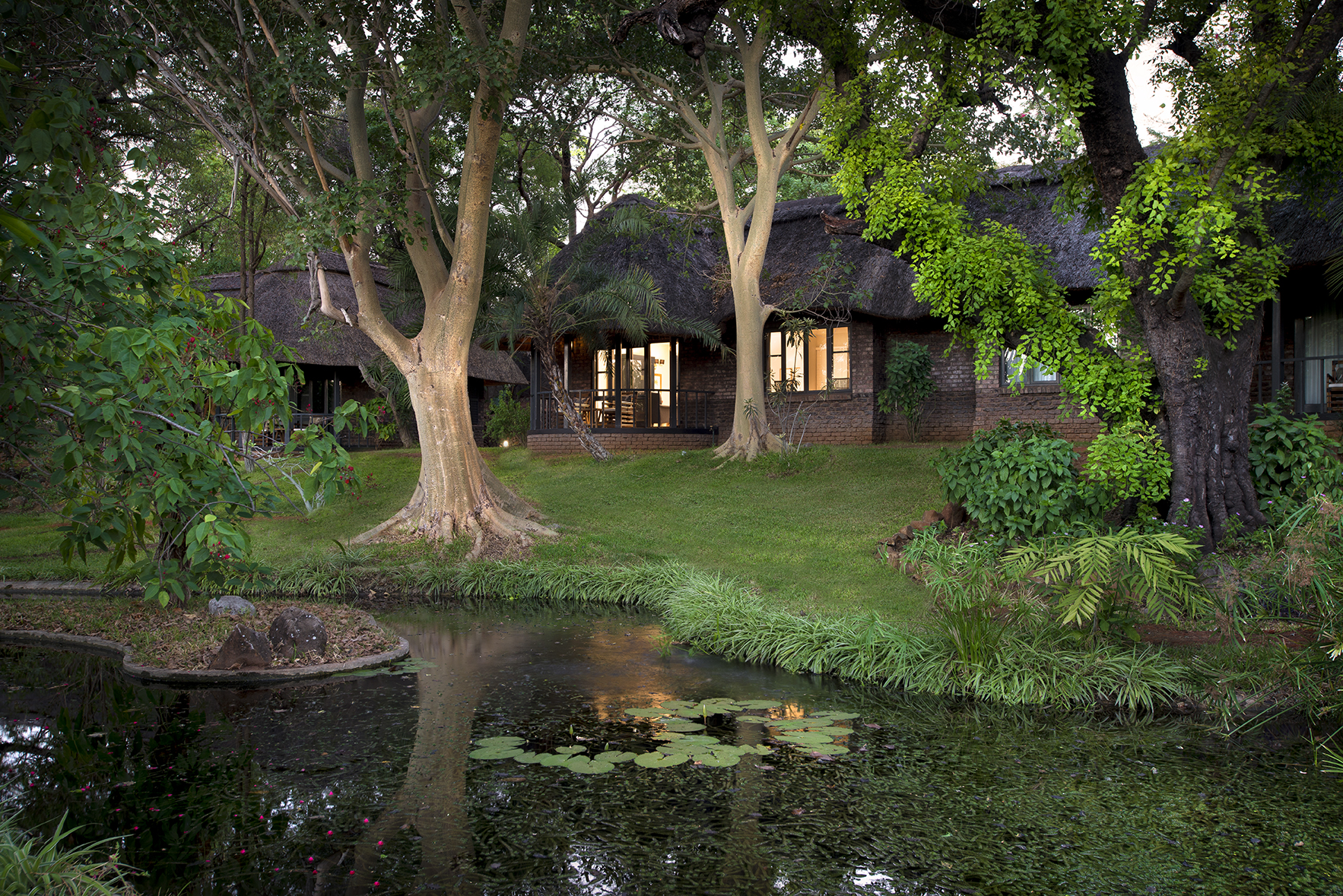 Afrikarma, Afrikarma Safaris, Afrikarma Safaris - Wildnis. Hautnah., Afrikarma.de, Bäume, Grassfläche, Fluss, Garten, Suiten, Wasserlielien, Stanley and Livingstone Boutique Hotel