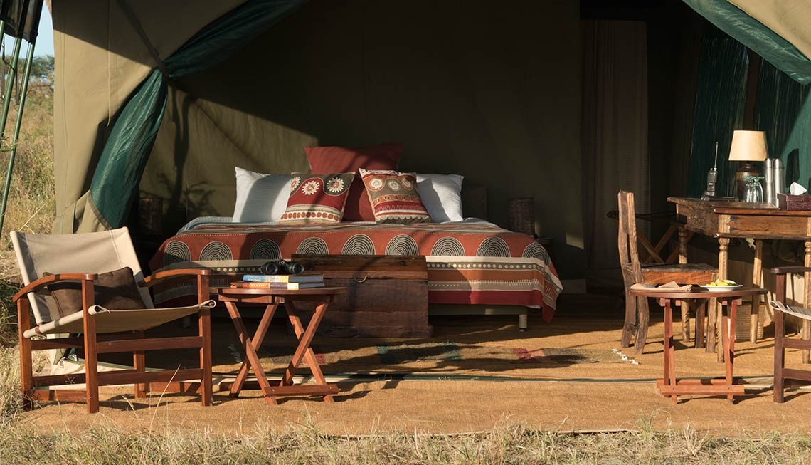 Chaka Camp: Das große Doppelbett in einem Gästezelt Chaka Camp, Große Migration, Große Wanderung, Mara River, Masek Lake, Ndutu Lake, Ngorongoro Conservation Area, Serengeti, Tansania, Wandercamp, Doppelbett, Gästezelt, Sekretär, Sessel, Afrikarma, Afrikarma Safaris, Afrikarma Safaris – Wildnis. Hautnah., afrikarma.de