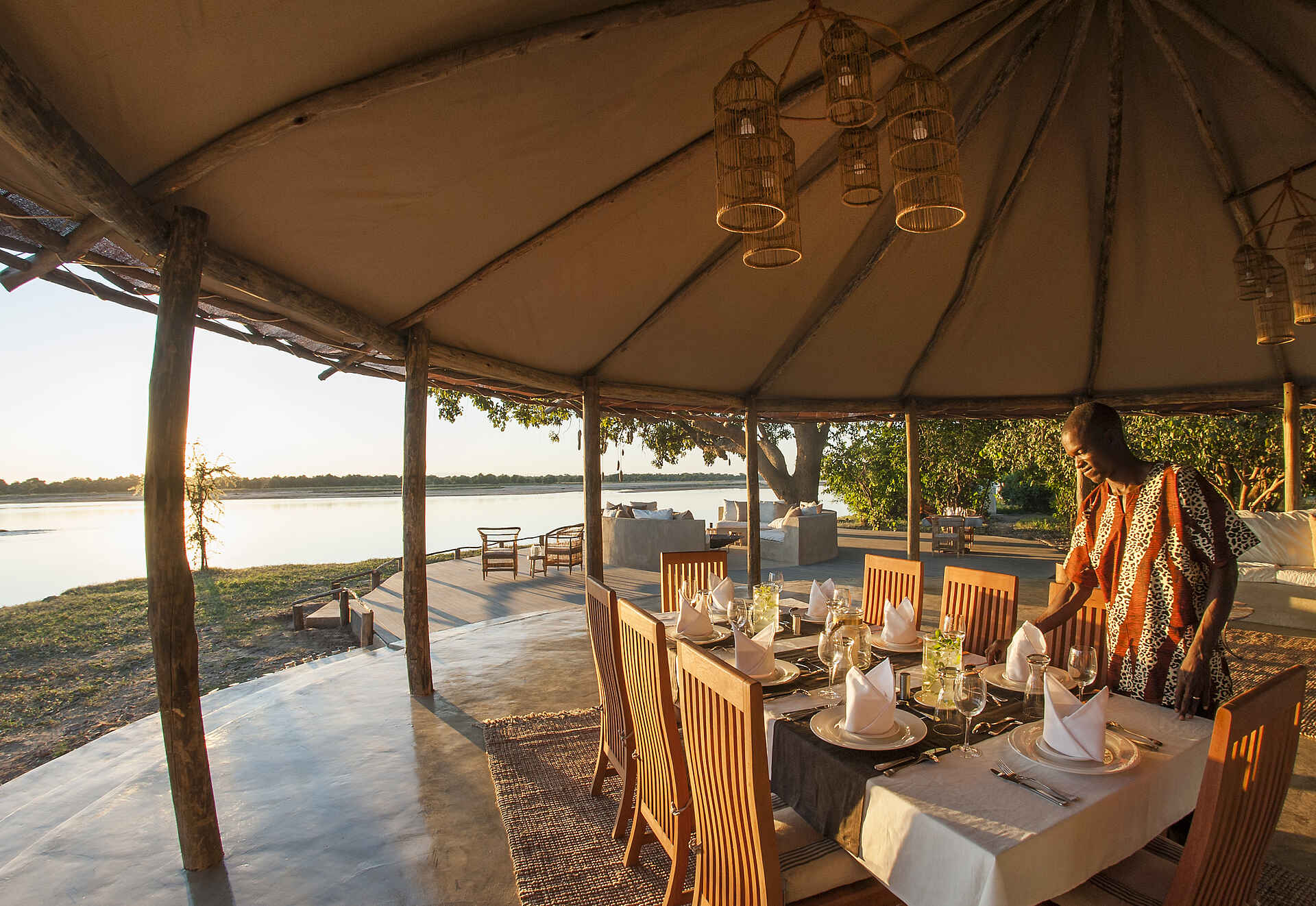 Kafunta Safaris, Kapamba River, Luangwa River, Lusangazi River, Sambia, South Luangwa, Three Rivers Camp, Dinner, Feuerstelle, Fluss, Flussufer, Gedeckter Tisch, Sofas, Sonnenuntergang, Speisebereich, Terrasse, Afrikarma, Afrikarma Safaris, Afrikarma Safaris – Wildnis. Hautnah., afrikarma.de, South Luangwa National Park