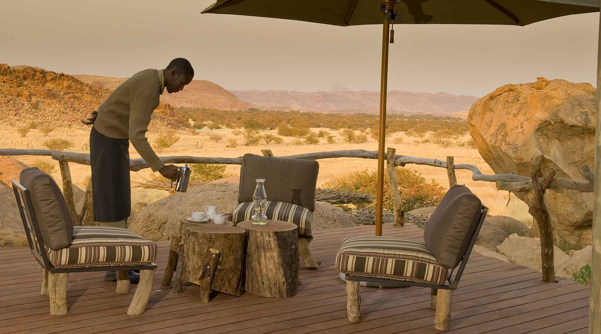 Afrikarma, Afrikarma Safaris, Afrikarma.de, Brandberg, Camp Kipwe, Damaraland, Drinks, Felsen, Gästechalet, Granit, Sonnenschirm, Strohdach, terrasse, Veranda, Mowani Collection