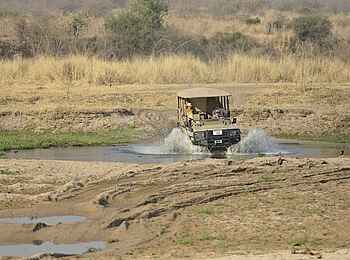 Ikuka Safari Camp: Geländewagen durchquert ein Wasserloch