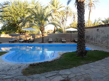 Fort Sesfontein: Am Pool sind Liegestühle und Sonnenschirme aufgestellt