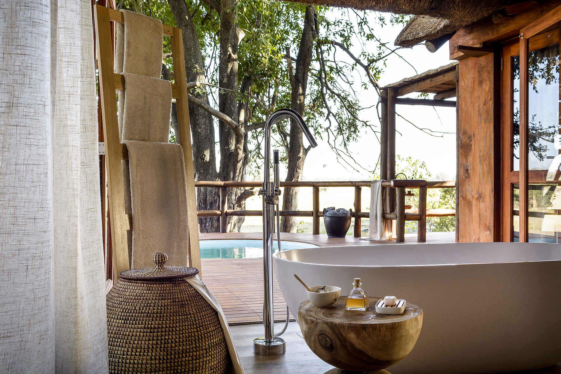 Afrikarma, Afrikarma Safaris, Afrikarma Safaris - Wildnis. Hautnah., Afrikarma.de, Sanctuary Chief's Camp, Badewanne, Bäume, Handtücher, Handtuchständer, Holzdeck, Holzzaun, Körbe, Ornamente, Seifen, Swimmingpool, Tisch