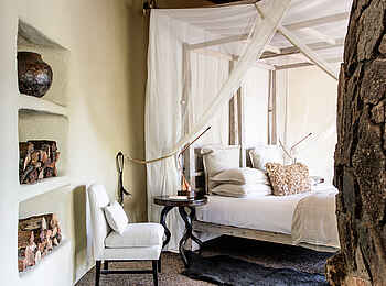 Singita Boulders Lodge: Blick ins Schlafzimmer und auf den Holzvorrat für den Kamin