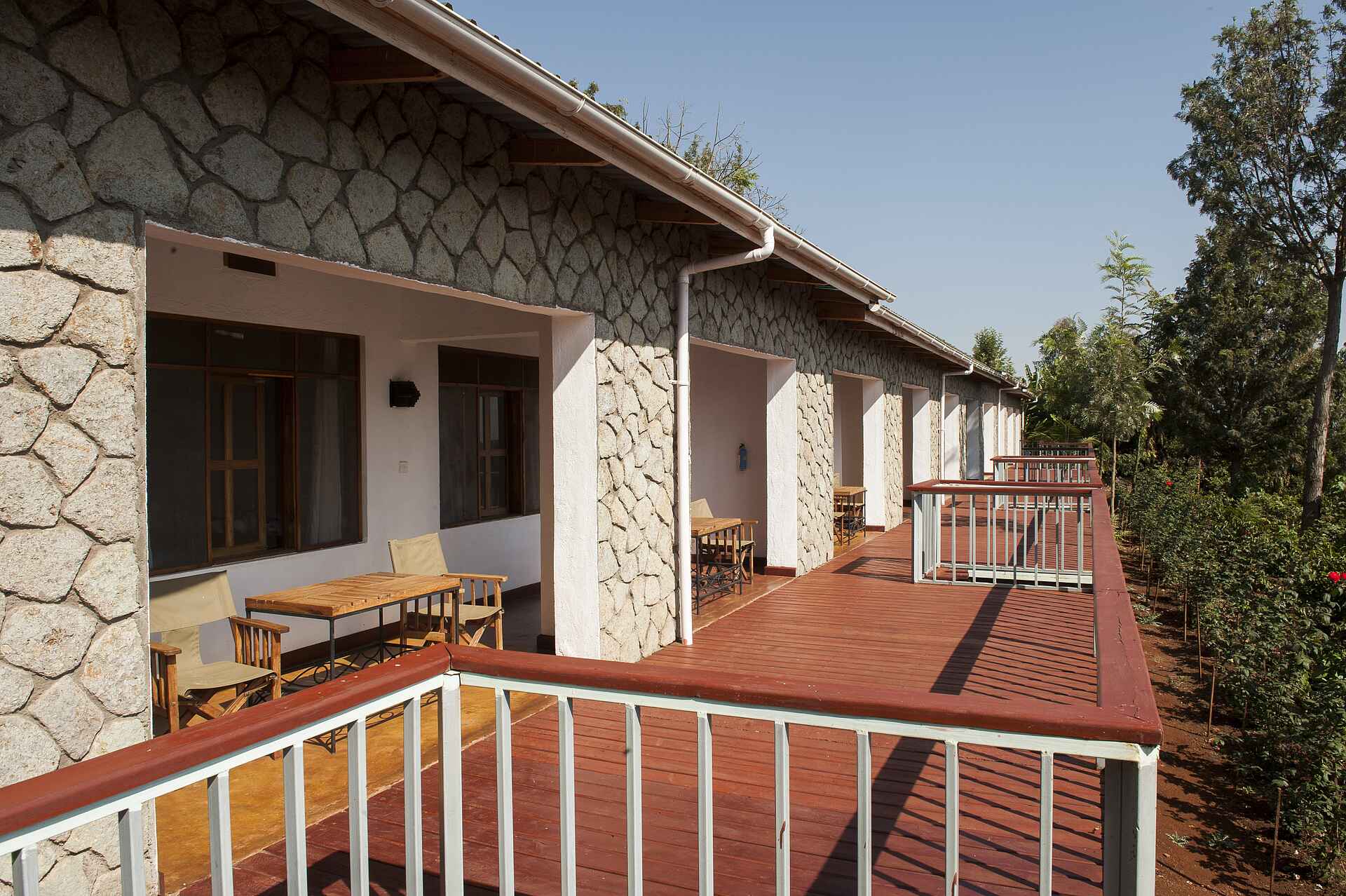 Tloma Lodge: Der Blick auf einen Teil der Gästeunterkünfte Ngorongoro Conservation Area, Ngorongoro-Krater, Tansania, Tloma Lodge, Gästeunterkünfte, Holzstühle, Holztische, Private Terrassen, Afrikarma, Afrikarma Safaris, Afrikarma Safaris – Wildnis. Hautnah., afrikarma.de