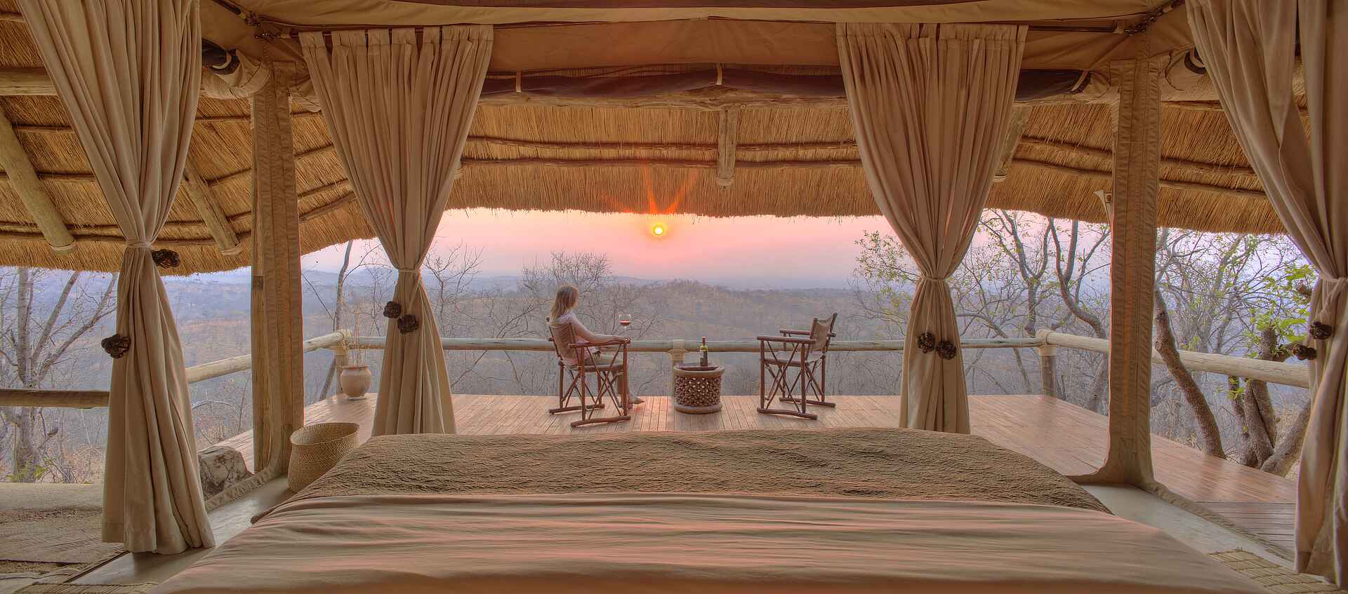 Ikuka Safari Camp: Blick von dem Doppelbett auf die Terrasse Chloe Sheridan-Johnson, Ikuka Safari Camp, Mark Sheridan-Johnson, Ruaha National Park, Ausblick, Doppelbett, Gästezelt, Himmelbett, Private Terrasse, Sicht, Sonnenuntergang, Afrikarma, Afrikarma Safaris, Afrikarma Safaris – Wildnis. Hautnah., afrikarma.de