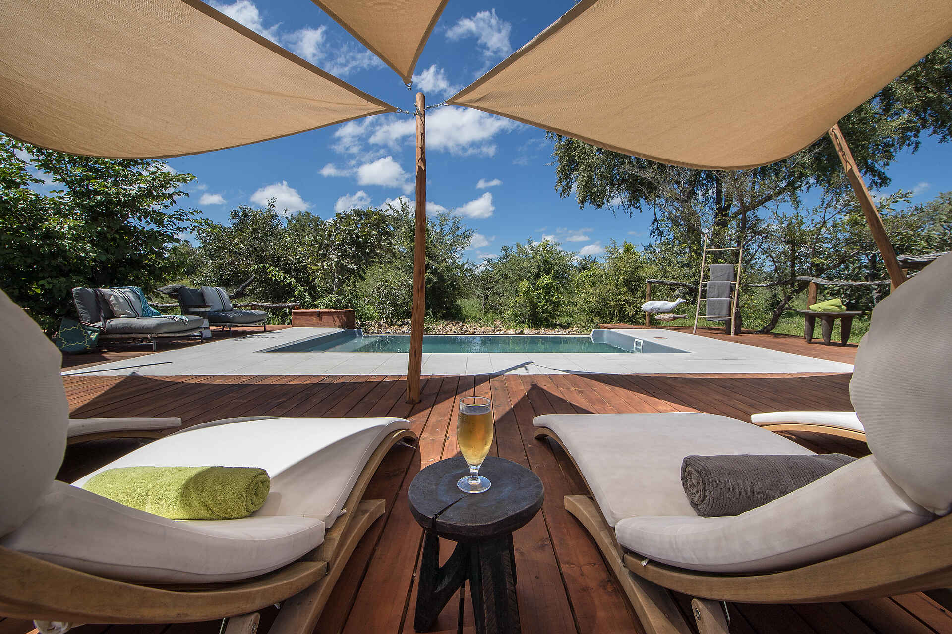 Afrikarma, Afrikarma Safaris, Afrikarma Safaris. Wildnis. Hautnah., Afrikarma.de, Bäume, Busch, Drink, Erfrischung, Glas, Handtücher, Kissen, Pool, Sonnenliegen, Sonnenschutz