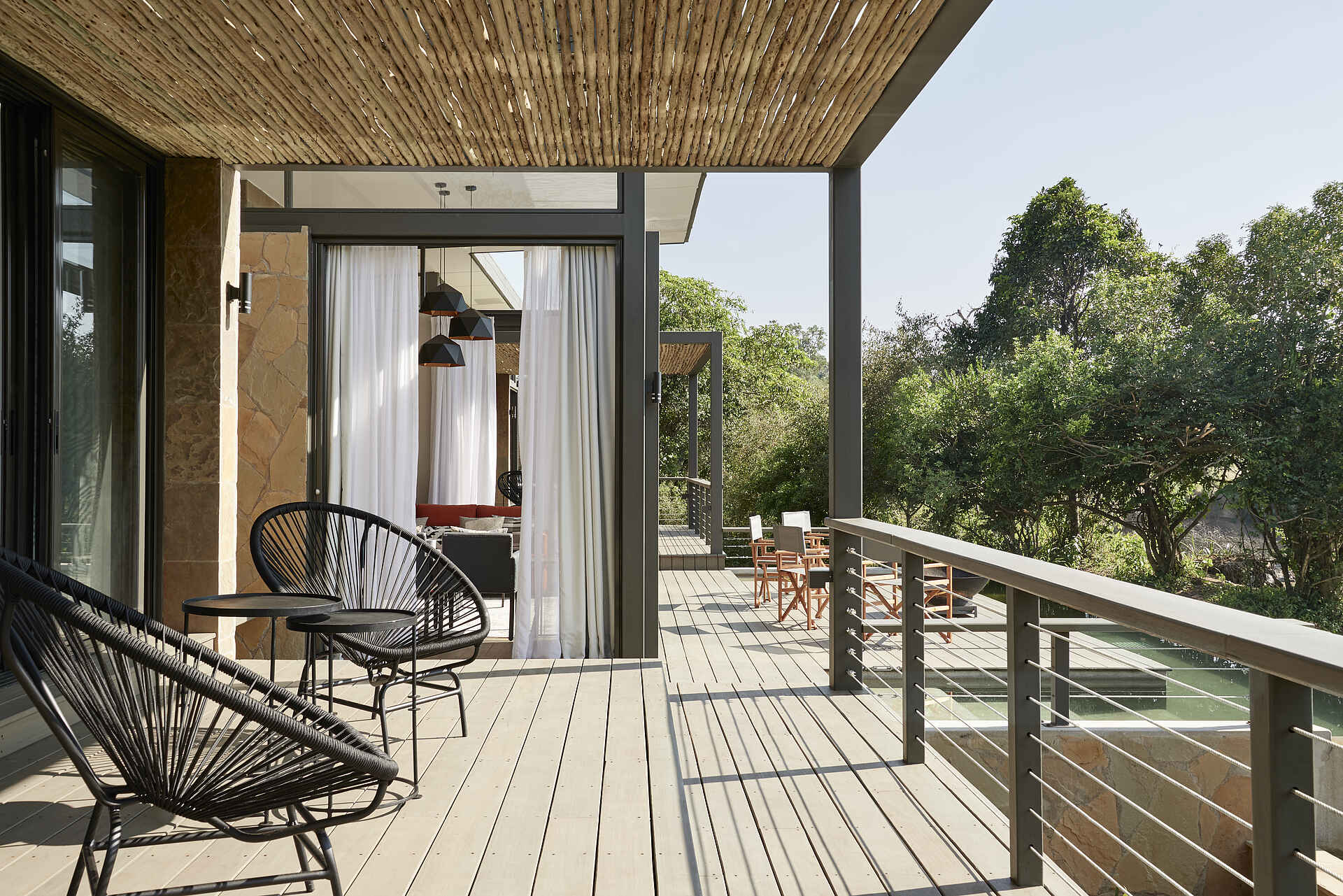 Afrikarma, Afrikarma Safaris, Afrikarma Safaris - Wildnis. Hautnah., Afrikarma.de, Bäume, Büsche, Holzdeck, Lampen, Sanctuary Olonana Geoffrey Kent Suite, Stühle, Tische, Vorhang, Zaun