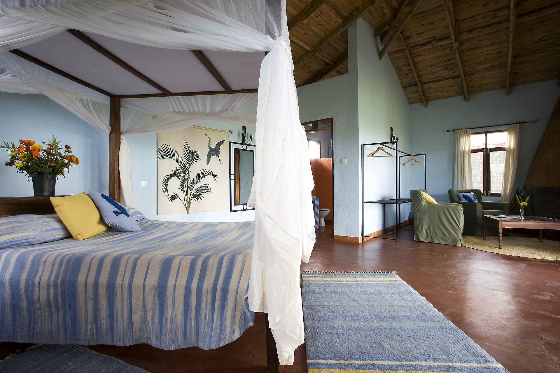 Tloma Lodge: Ein Chalet mit einem Doppelbett Ngorongoro Conservation Area, Ngorongoro-Krater, Tansania, Tloma Lodge, Chalet, Doppelbett, Gästeunterkunft, Himmelbett, Kamin, Kleiderstange, Sessel, Afrikarma, Afrikarma Safaris, Afrikarma Safaris – Wildnis. Hautnah., afrikarma.de