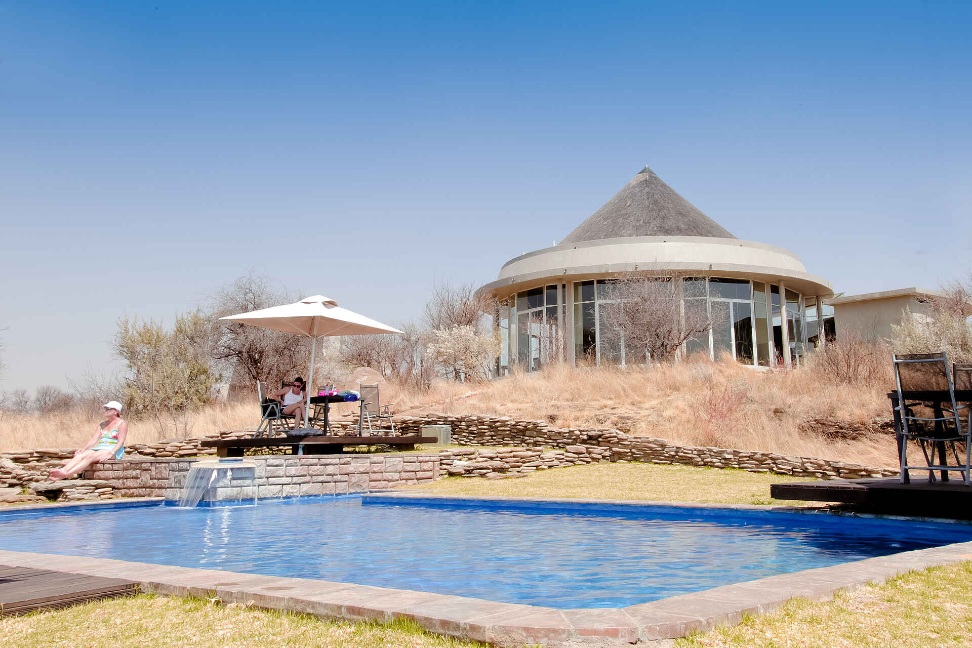 Naankuse Lodge: Main Lounge und Swimming Pool Airport, Auffangsstation, Auswilderung, Auszeichnung, Carnivoren, Charity, Charity Lodge, Fleischfresser, Flughafen, Gepard, Geparden, Hochzeit, Koch, Küche, Leopard, Leoparden, Naankuse, Naankuse Foundation, Naankuse Lodge, Naankuse Reservat, Naankuse Reservation, Naankuse Schutzgebiet, Naankuse Stiftung, Namiba, Raubtiere, Reservat, Safari, San, San-Volk, Seminar, South East Namibia, South Namibia, Südnamibia, Südostnamibia, Tagung, Tierschutz, Tracking, Windhoek, Wohltätigkeit, Ansicht, Hauptgebäude, Main Building, Main Lounge, Swimming Pool
