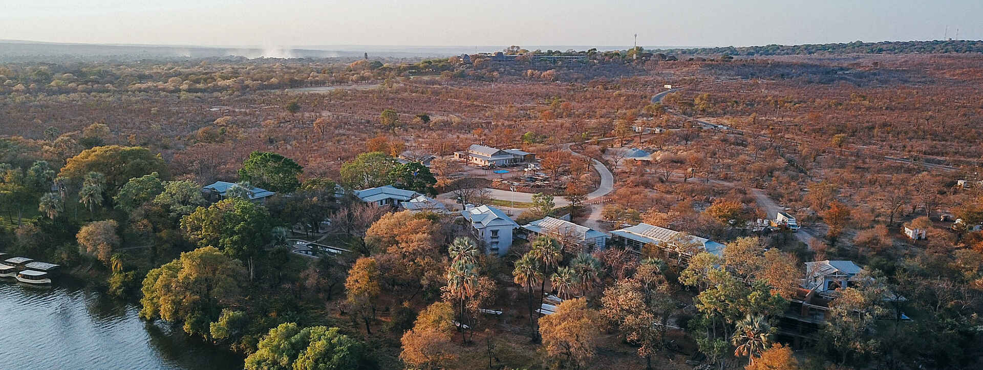 Im Hintergrund des Palm River Hotels sieht man die Gischt der Viktoriafälle aufsteigen.