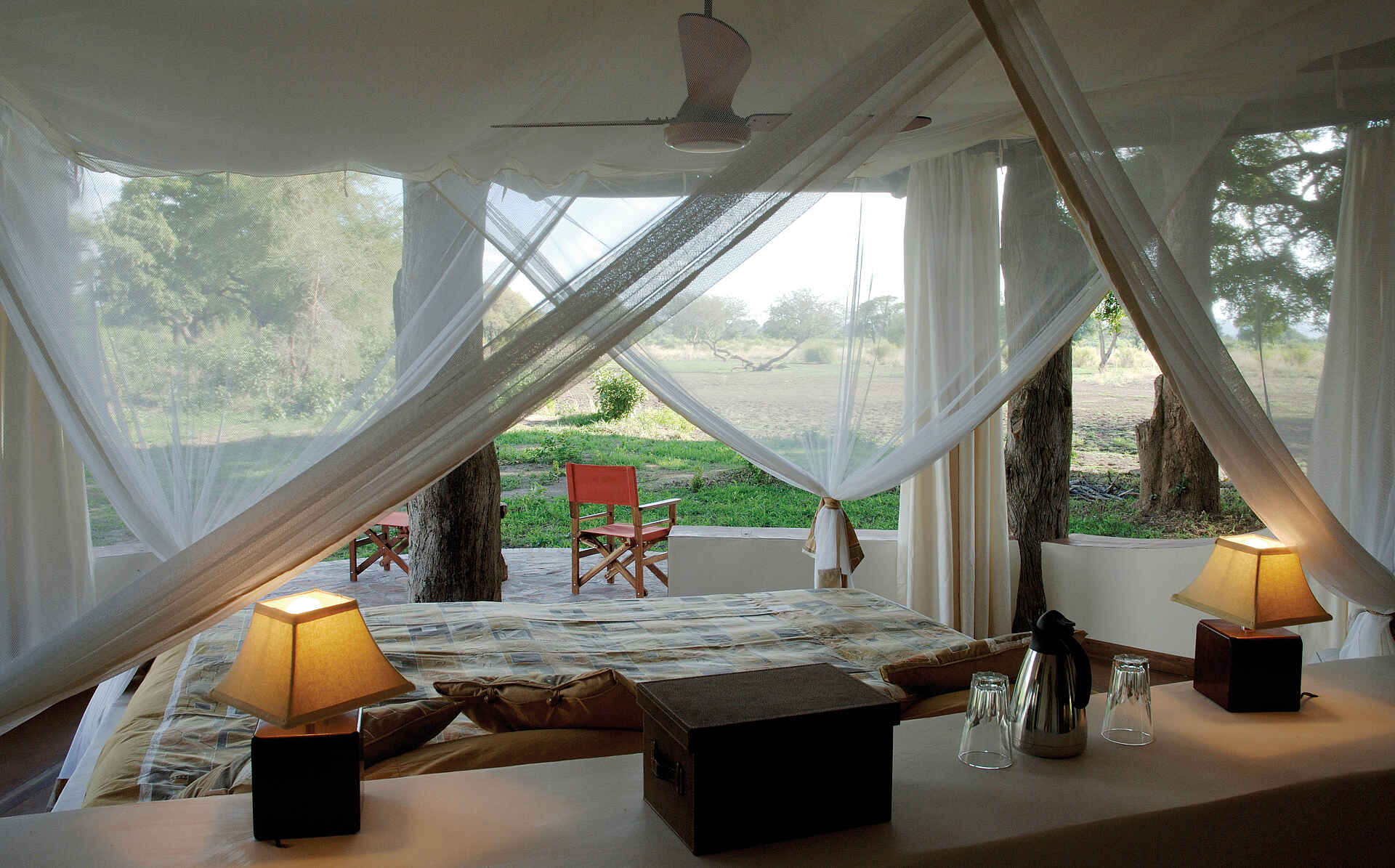 Luangwa Safari House: Blick übers Bett nach außen Luangwa, Luangwa River, Luangwa Safari House, Luangwa-Tal, Robin Pope, RPS, South Luangwa National Park, Doppelbett, Moskitonetz, Nachttischlampe, Schlafzimmer, Afrikarma, Afrikarma.de, Robin Pope Safaris