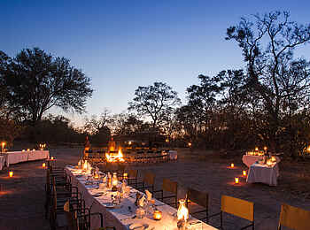 Little Machaba Camp: Stimmungsvolle Abendszenerie beim Dinner vor der Hauptlodge