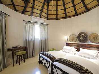 Onguma Bush Camp: Waterhole Chalet - Doppelbett unter einem Reetdach