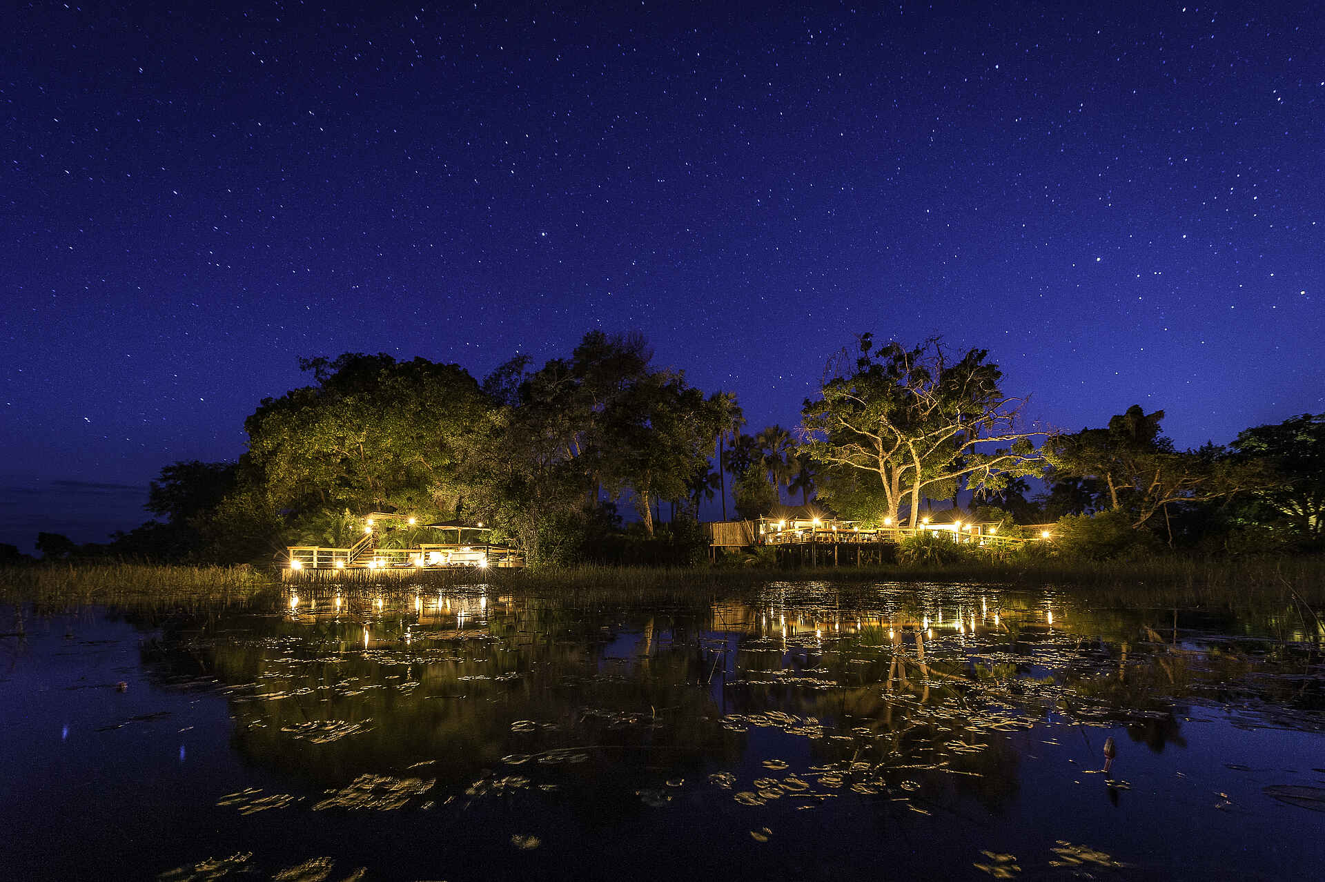 Pelo Camp: Nächtlich erleuchtetes Camp Adventure Camp, Afrikarma, Jao Konzession, NG 25, Okavango-Delta, Pelo, Pelo Camp, Safari, Gesamtansicht, Hauptzelt, Wassercamp, Wilderness Safaris, Afrikarma Safaris, Afrikarma Safaris - Wildnis. Hautnah., afrikarma.de