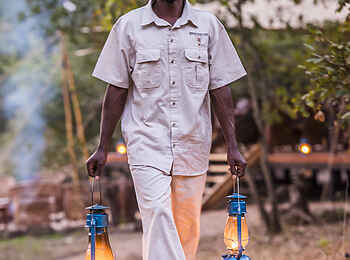 Mukambi Fig Tree Bush Camp: Ein Angestellter beim Verteilen der Öllampen