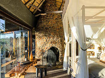 Singita Boulders Lodge: Schlafbereich mit Kamin und Blick nach draußen
