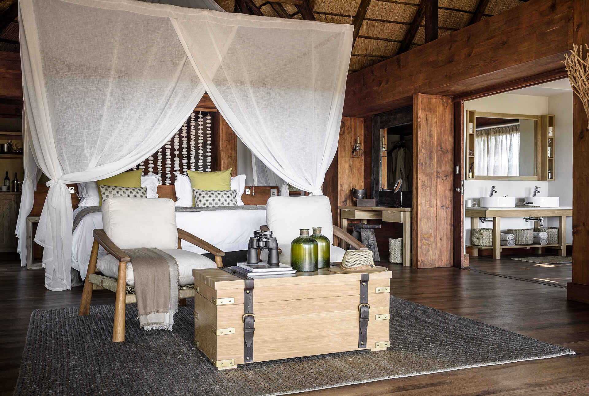 Afrikarma, Afrikarma Safaris, Afrikarma Safaris - Wildnis. Hautnah., Afrikarma.de, Sanctuary Chief's Camp, Decken, Flaschen, Handtücher, Holzbalken, Holzboden, Kingsize-Bett, Kissen, Körbe, Moskitonetz, Ornamente, Sofasitze, Spiegel, Strohdach, Teppich, Truhe, Waschbecken