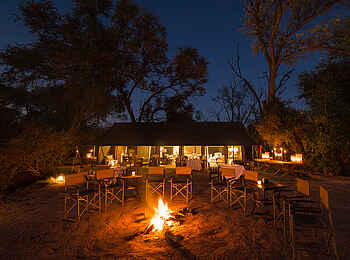 Little Machaba Camp: Feuerstelle bei Nacht mit der Hauptlodge im Hintergrund