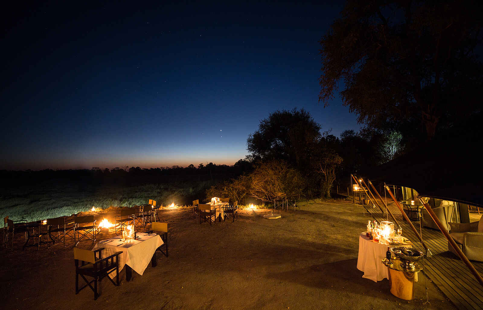 Little Machaba Camp: Außenbereich der Hauptlodge, eingedeckt zum Dinner. Little Machaba Camp: Außenbereich der Hauptlodge, eingedeckt zum Dinner.