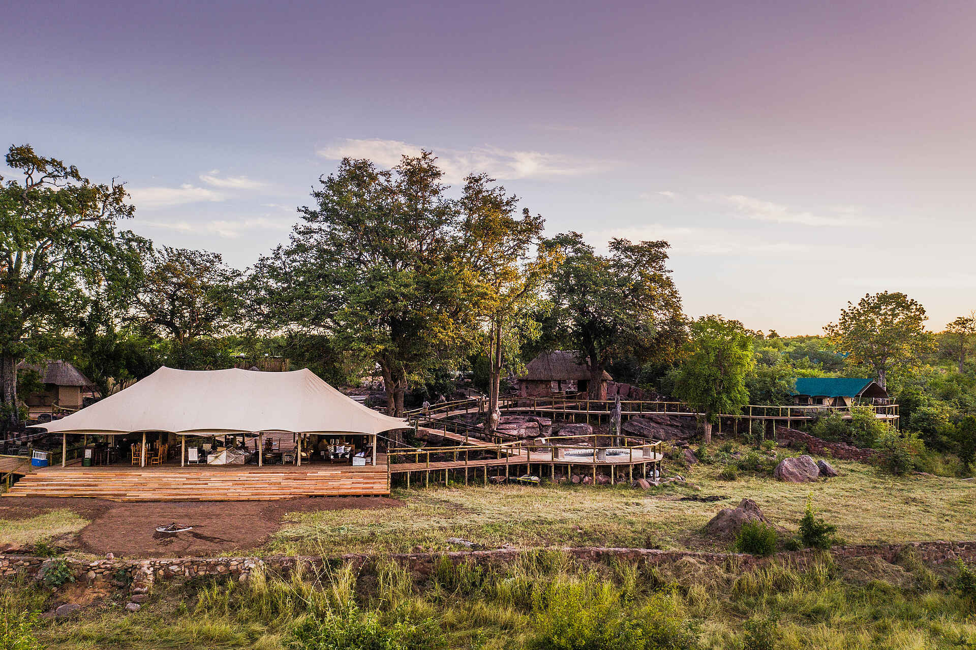Afrikarma, Afrikarma Safaris, Afrikarma Safaris - Wildnis. Hautnah., Afrikarma.de, Deteema Springs Camp, Bäume, Büsche, Erhöhte Gehwege, Gras, Hauptbereich, Luxuszelte