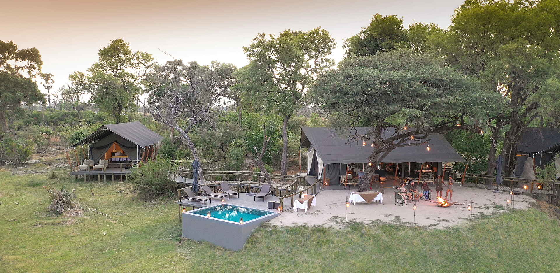 Gomoti Private Camp: Main Area Afrikarma, Afrikarma Safaris, Afrikarma Safaris. Wildnis. Hautnah., Afrikarma.de, Camp, Gomoti Private, Gomoti Private Camp, Bäume, Feuer, Main Area, Pool, Sonnenliegen, Tisch, Zelte