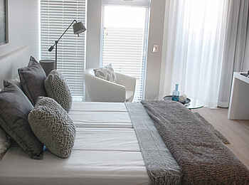 Swakopmund Luxury Suites: Sessel und Bett Standard Grey