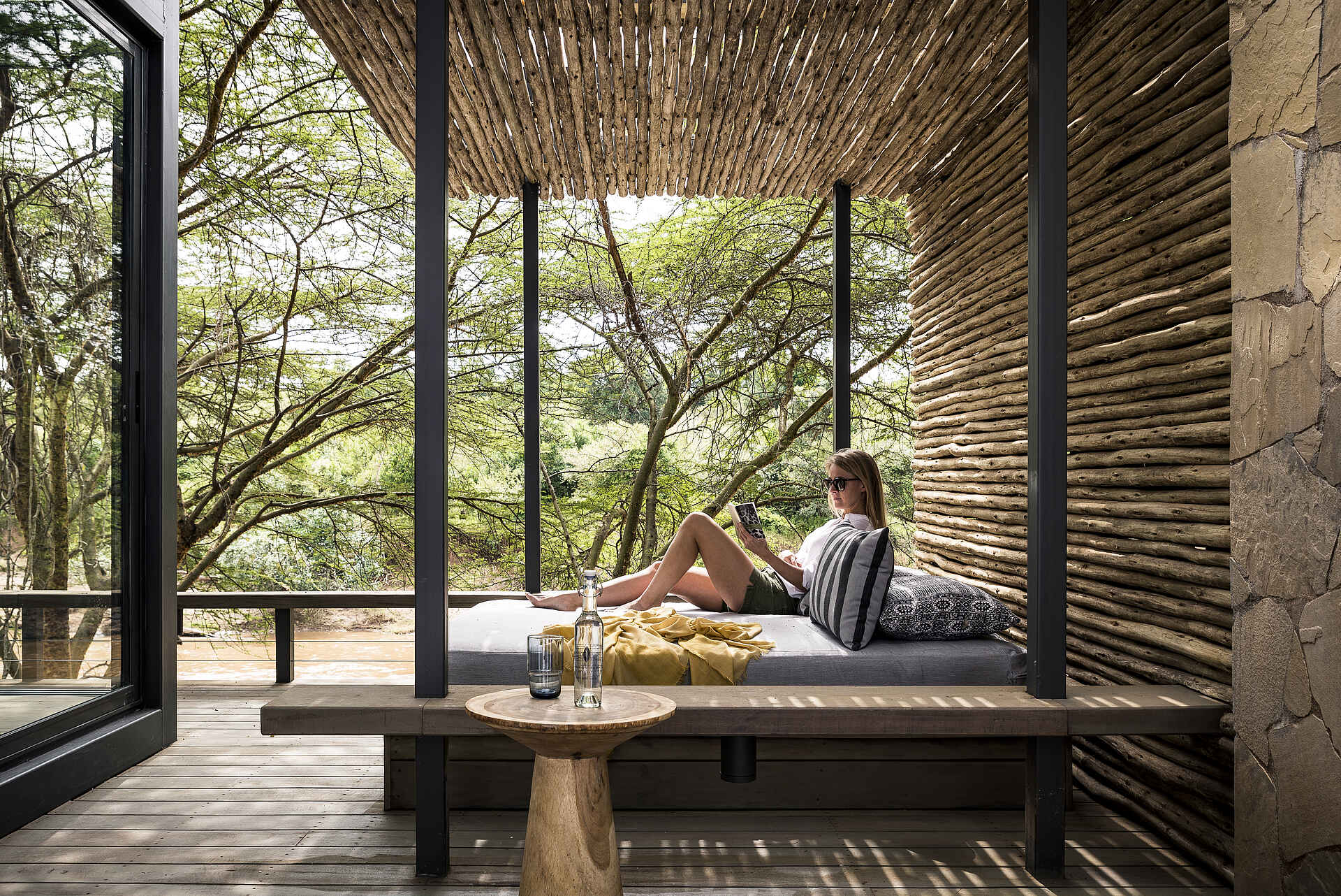 Bank, Bäume, Buch, Büsche, Decke, Flasche, Fluß, Gast, Glas, Holzdeck, Holzwand, Kissen, Sofabett, Sonnenbrille, Tisch, Afrikarma, Afrikarma Safaris, Afrikarma Safaris - Wildnis. Hautnah., Afrikarma.de, Sanctuary Olonana